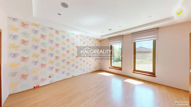 A room with large windows and floral wallpaper in a family house.