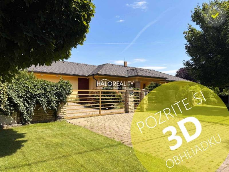 A family house in Komárno with a spacious garden, a paved driveway, and a hedge.