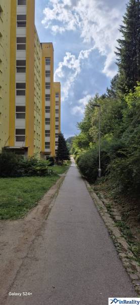 Yellow apartment building on Moskovská Street in Banská Bystrica next to the sidewalk and greenery.