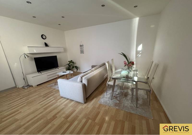 Living room in a two-room apartment with a sofa, television, and dining table.