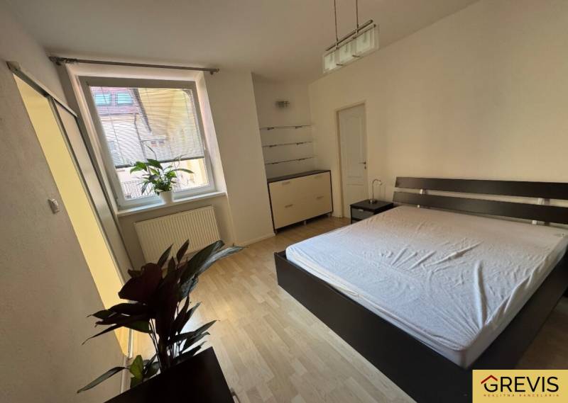 A bedroom with a double bed, houseplants, and a dresser in a two-room apartment.