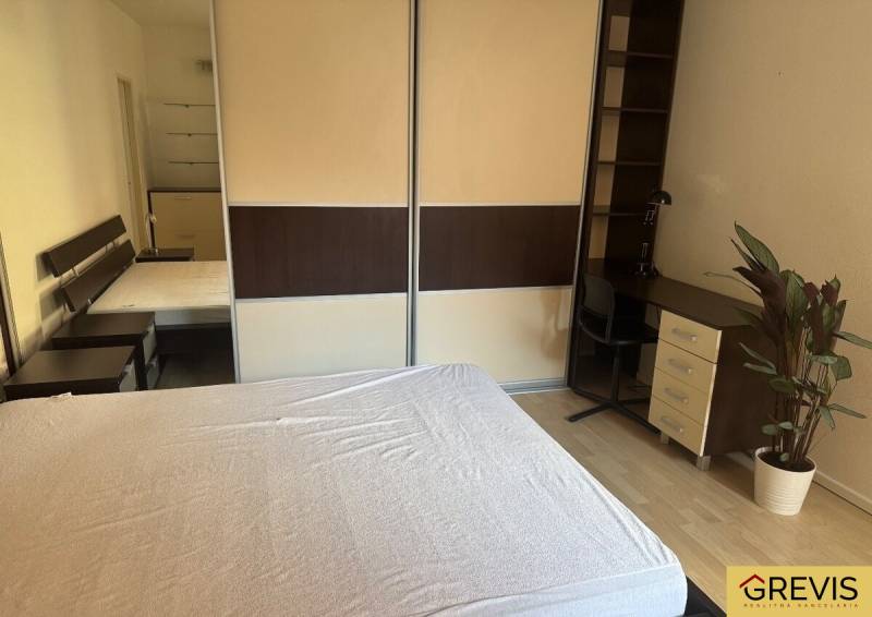 Bedroom in a 2-room apartment with a wardrobe, table, and plant.