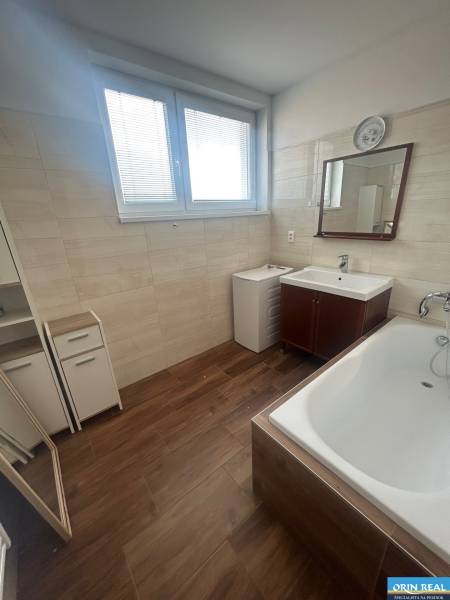 Bathroom in a 3-room apartment with a bathtub, mirror, and wood decor on the floor.