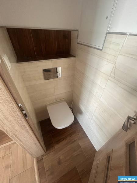 A toilet with light tiles and wooden details in a 3-room apartment.