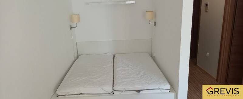 A double bed with wall lamps in a two-room apartment.