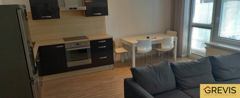 Kitchen and living room in a 2-room apartment with a modern kitchen unit and dining table.