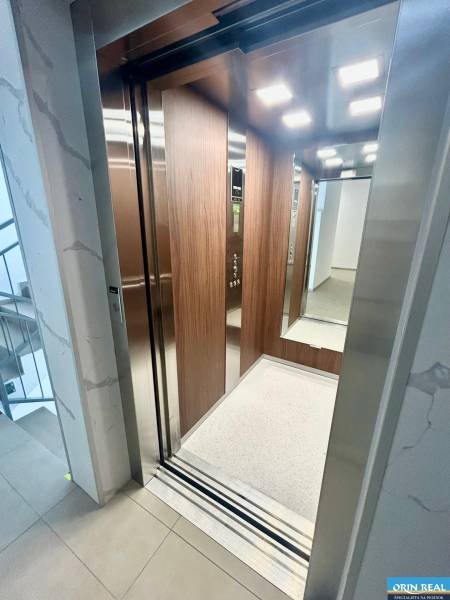 An open elevator in a 3-room apartment with wooden paneling and lighting.