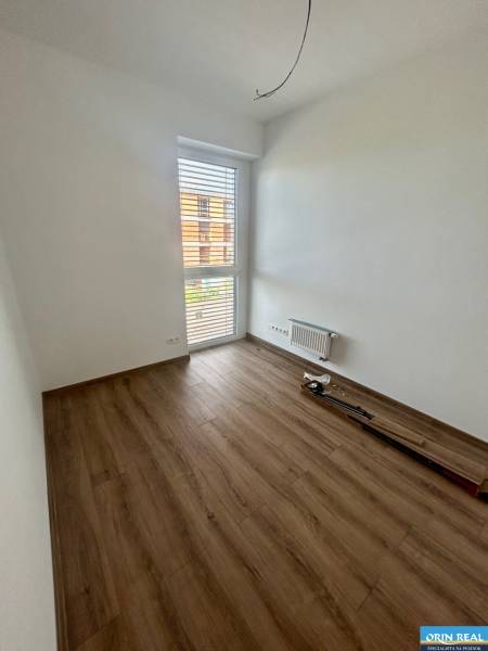 An empty room with laminate flooring and a large window in a 3-room apartment.
