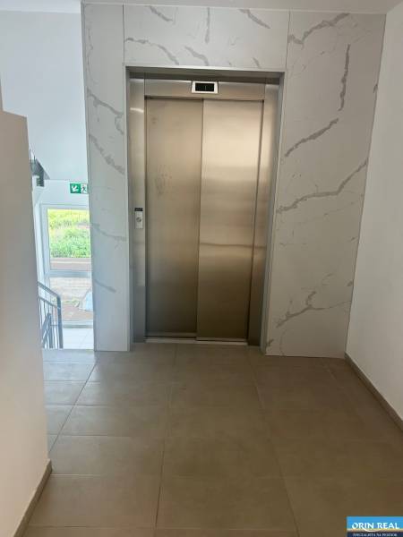 Elevator in the hallway of a 3-room apartment with tiles and a window.