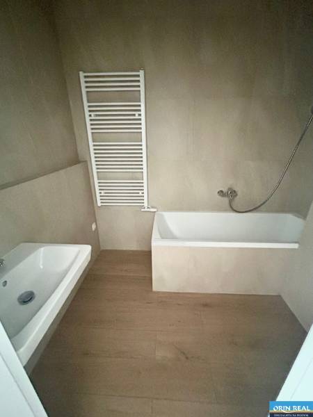 A bathroom with a bathtub and a ladder radiator in a 3-room apartment, dark floor.