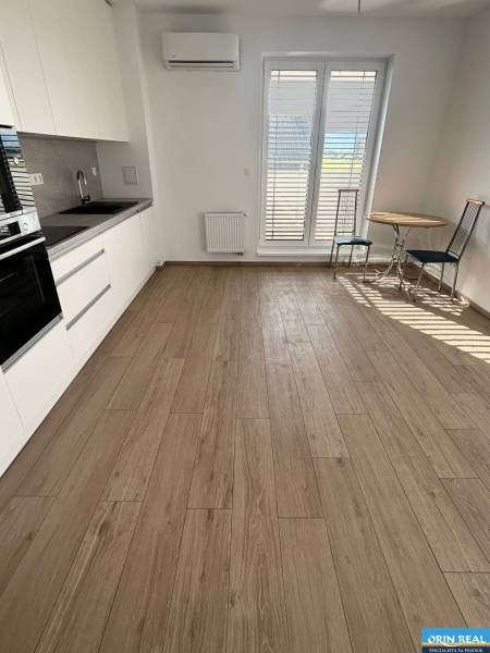 A kitchen in a 3-room apartment with wooden flooring, a dining table, and French windows.