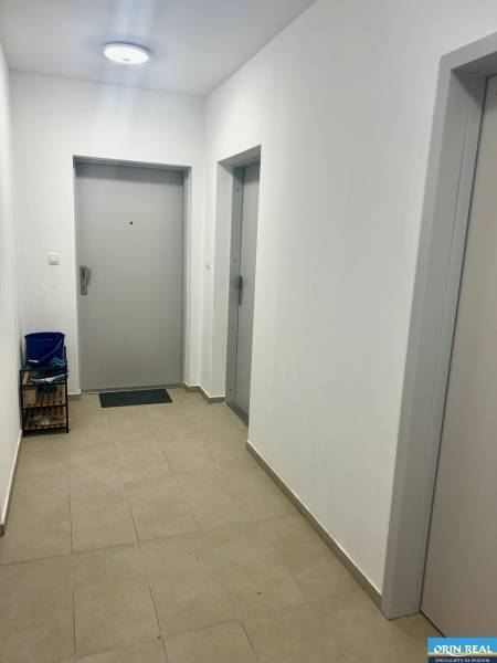 A hallway in a 3-room apartment with doors and lighting, tiles on the floor.