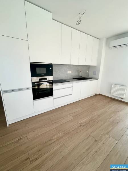 A kitchen in a 3-room apartment with white cabinets, appliances, and wooden flooring.