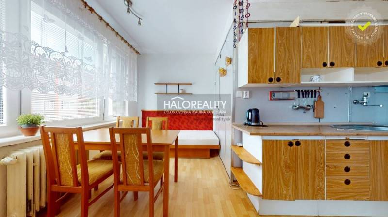 A kitchen in a 4-room apartment with wooden furniture and a dining table.