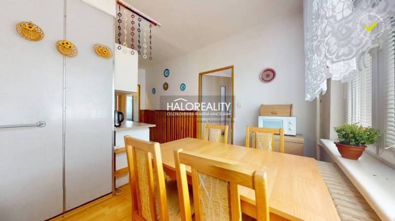 Dining room in a 4-room apartment with a wooden table and a plant on the windowsill.