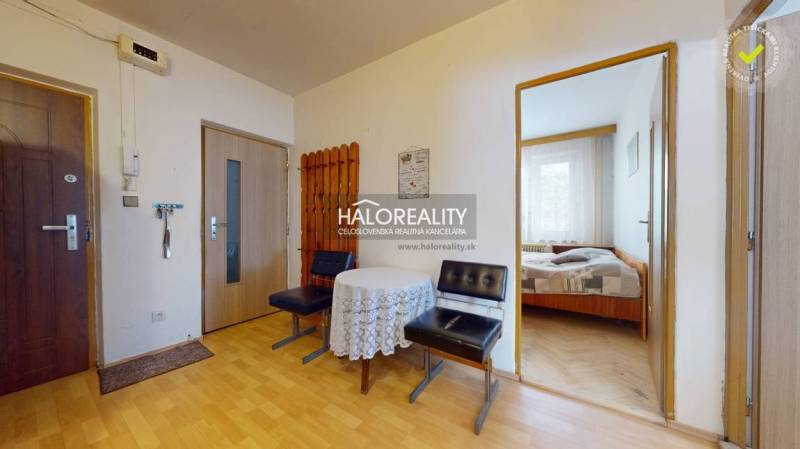 The hallway of a 4-room apartment with wooden furniture, a table, and an entrance to the bedroom.