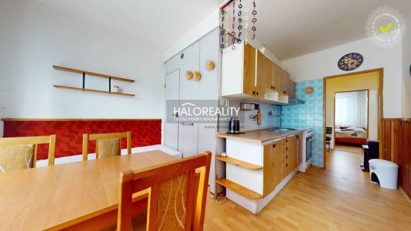 A kitchen in a 4-room apartment with wooden furniture and a dining table.