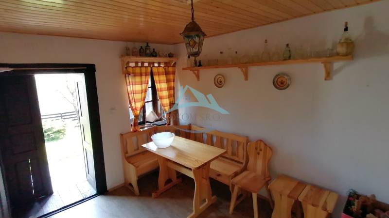 The rustic interior features a wooden bench and table, with furniture complementing the atmosphere of a family home.