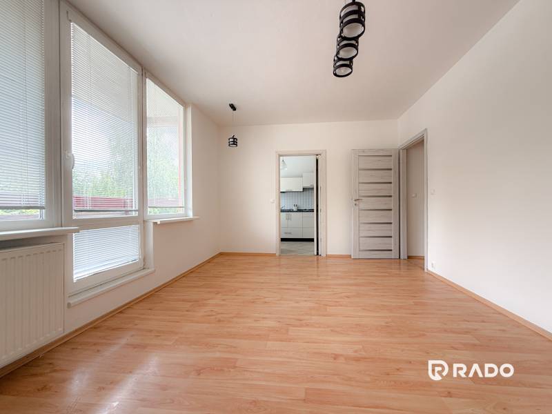 A spacious room in a 3-room apartment with wooden flooring and large windows.