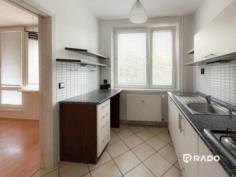 A kitchen in a 3-room apartment with light tiling and furniture.