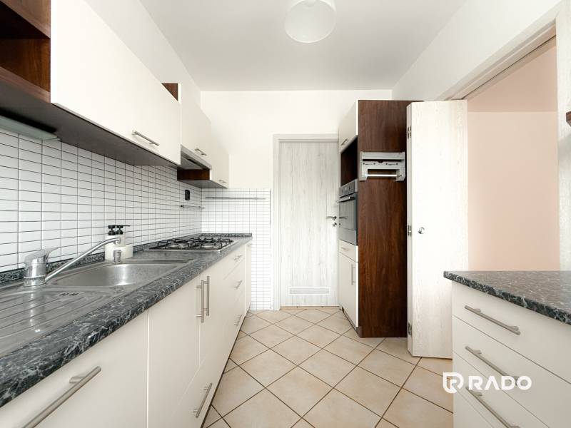 Kitchen of a 3-room apartment with a tiled wall, double sink, and built-in oven.