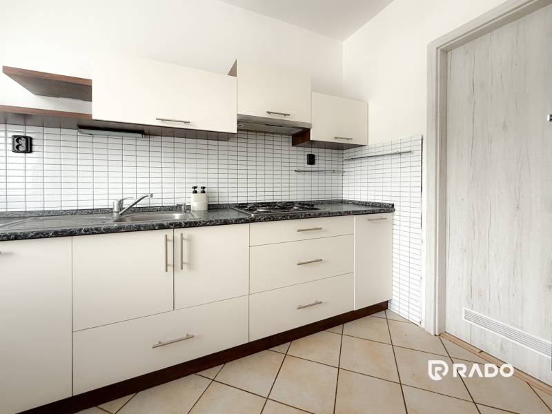 A kitchen unit with white doors and a black countertop in a 3-room apartment.