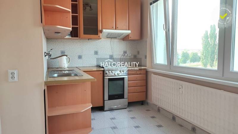 A kitchen in a 4-room apartment with wooden cabinets and a large window.
