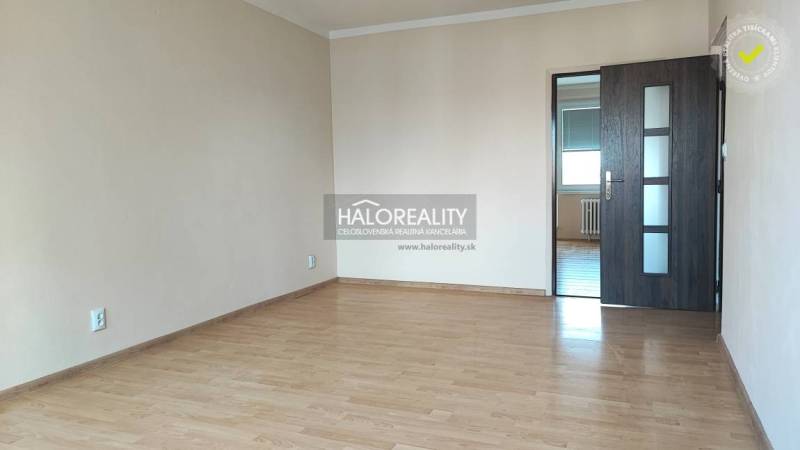 A spacious room in a 4-room apartment with laminate flooring and dark doors.