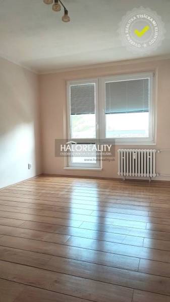 A room with a wooden floor in a 4-room apartment, equipped with a radiator and windows with blinds.