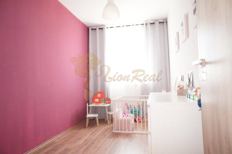 Children's room in a family house with a pink wall, toys, and a crib.