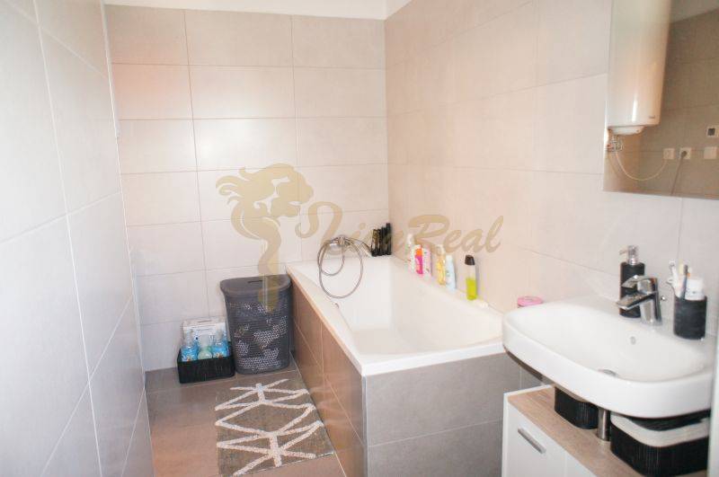 A bathroom in a family house with a bathtub, a sink, and storage baskets for laundry.