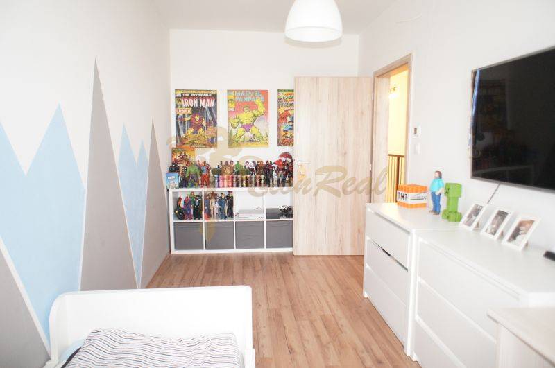 Children's room with figurines, comics on the wall, and white furniture in a family house.