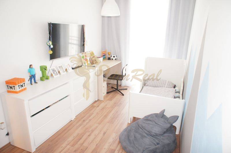 A children's room in a family house with white furniture and wooden flooring.