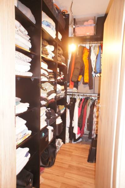 A wardrobe with shelves and hangers full of clothes in a family house.