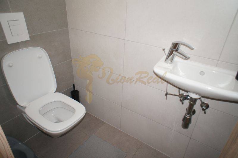 A toilet with a sink in a family house is tiled with minimalist furnishings.