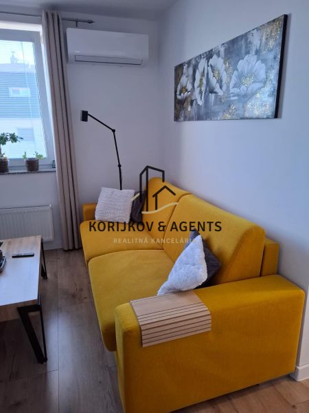 Yellow sofa, table, decorations, and wooden decor flooring in a 2-room apartment.