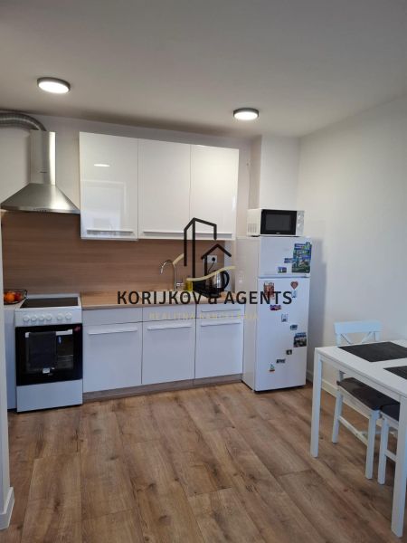 A kitchen in a 2-room apartment with white cabinets and a wood-patterned floor.