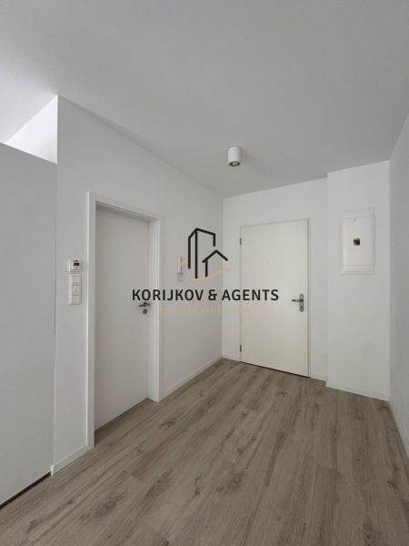 A hallway with white walls and a wooden decor floor in a studio apartment.