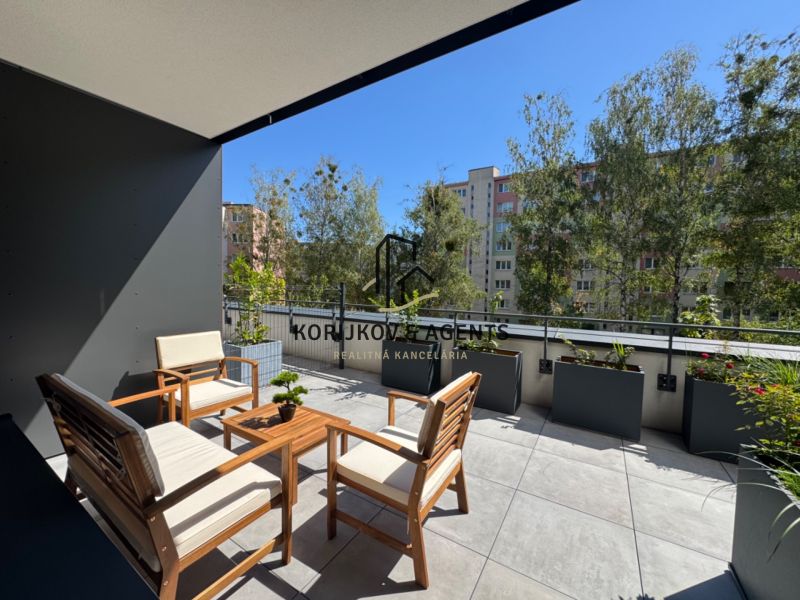 A terrace with wooden garden furniture surrounded by greenery on Popradská Street in Košice.