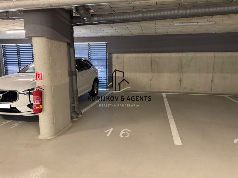 Underground parking lot with a parking space near a car and a fire extinguisher.