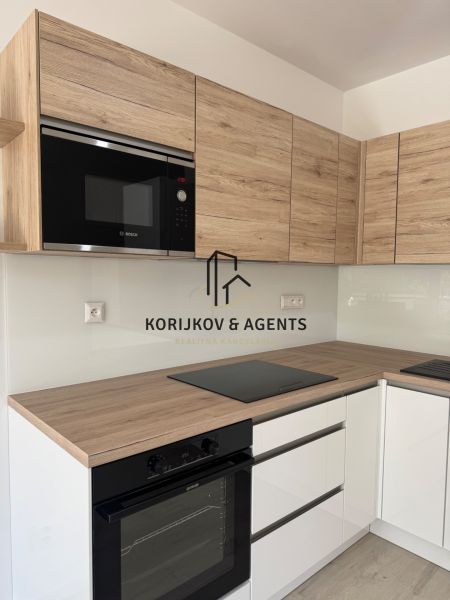 A kitchen in a studio apartment with wooden decor and built-in appliances.