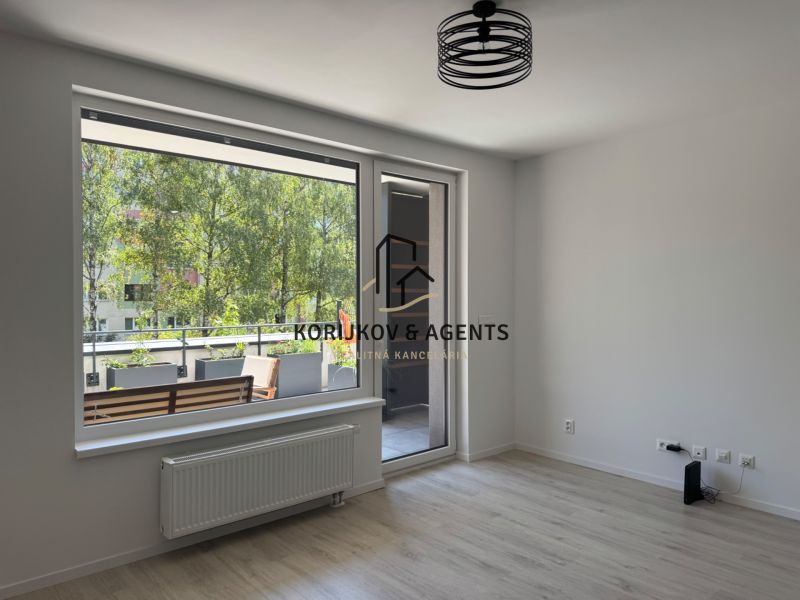 A one-room apartment with a large window and a balcony, floor with wooden decor.