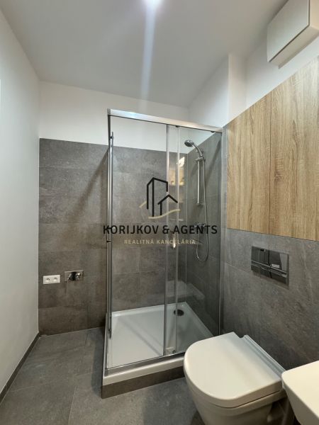 Bathroom with a modern shower cabin and gray ceramic tiles in a studio apartment.