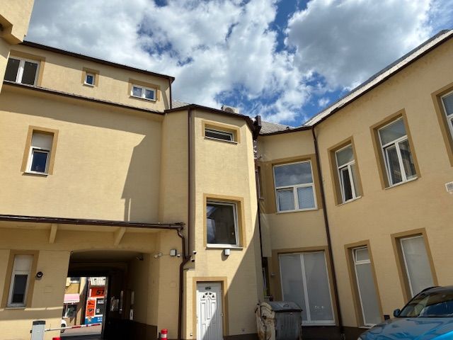 Commercial premises on Ružová Street in Ilava with a multi-story building and a parked car.