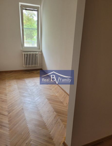 A room with a wooden floor and a radiator in a 3-room apartment.