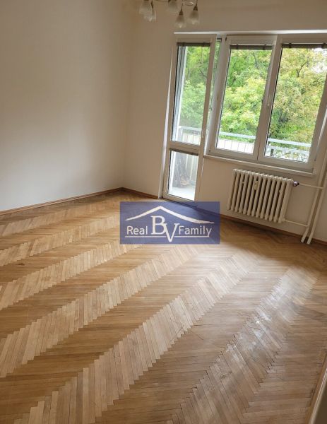 A room in a 3-room apartment, wooden parquet floors, large window, view of nature.