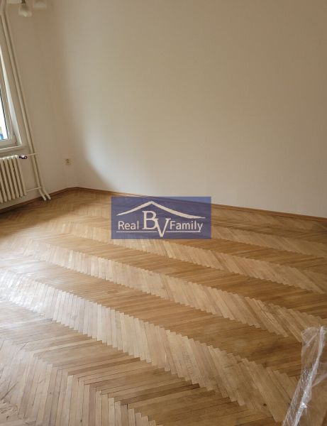 An empty room in a 3-room apartment with wooden parquet flooring and a radiator.