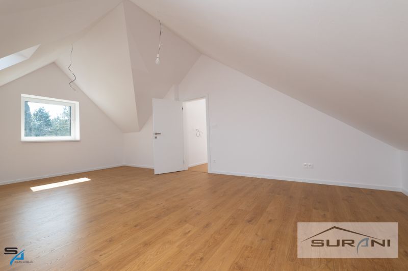 An attic room in a family house with a wooden decor floor and a slanted ceiling.