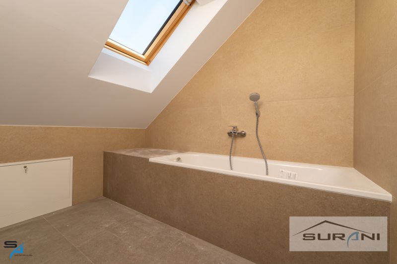 A bathroom in a family house with a bathtub and a skylight.