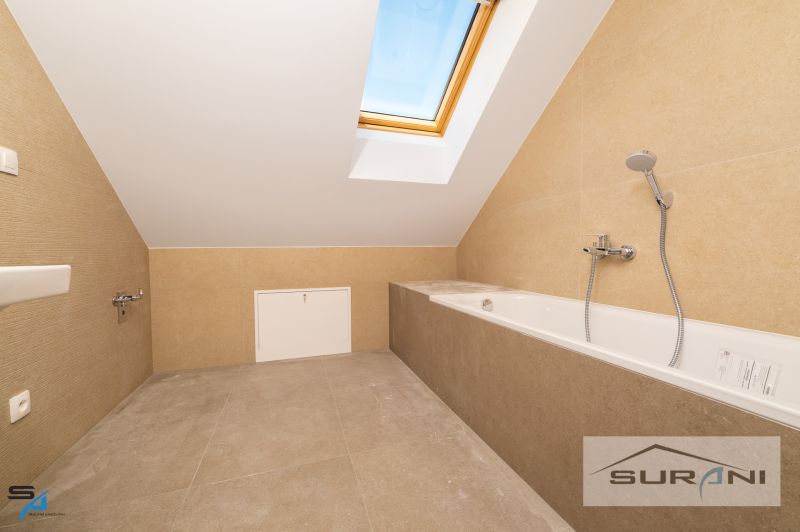 Bathroom with a bathtub and a skylight in a family house.